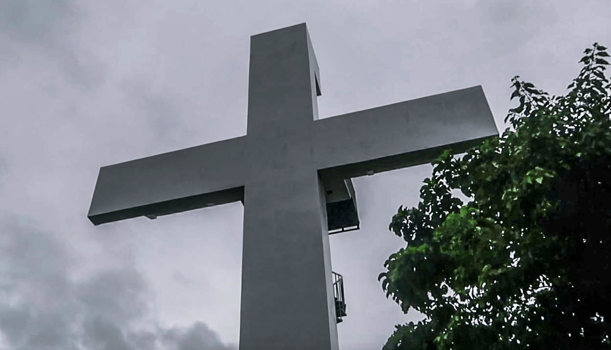 big white cross at the top of the hill at enchanted cave park in bolinao pangasinan philippines